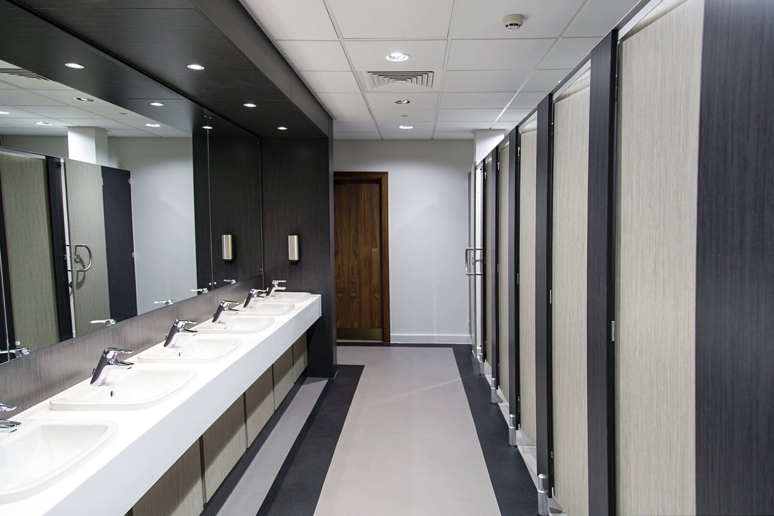 hygiene bathrooms, clean stall doors on right, taps on left, and a clear walkway