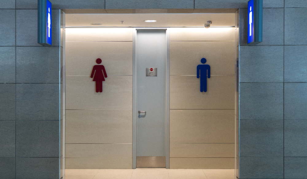 Front view of the entrance to a washroom with man and woman signs on a marble wall.