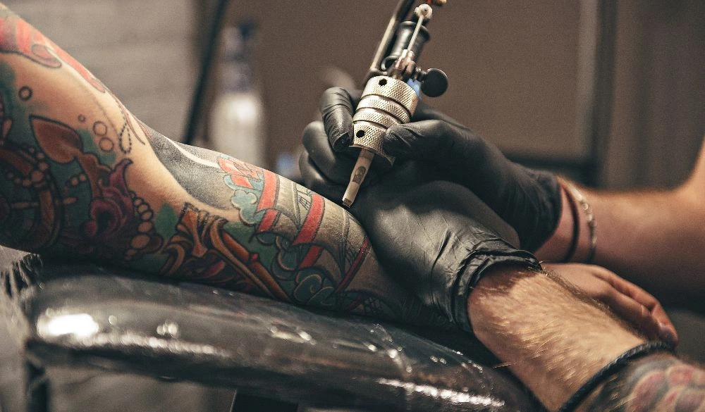 A female arm being tattooed by a professional tattoo artist.