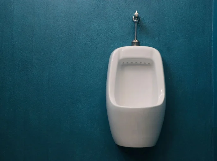 One ceramic urinal in a blue restroom.