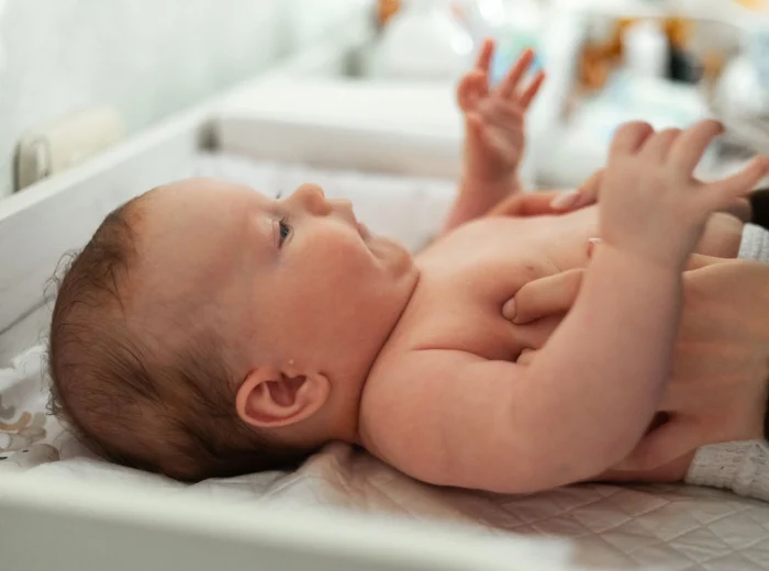 A baby lying down and being changed on a white, wall-mounted unit.