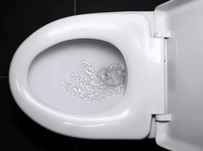 A birds-eye shot of a white toilet with water flushing.