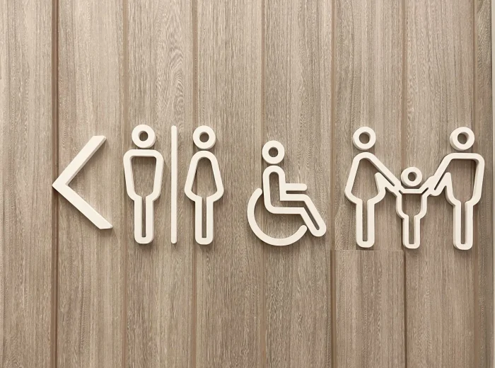 A wooden panel with white cut out signage for bathrooms.