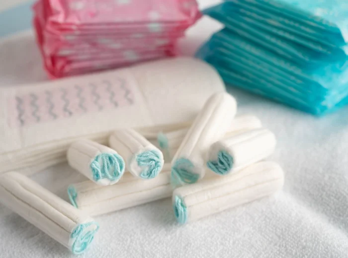 An assortment of period products including pads and tampons on a soft white surface.