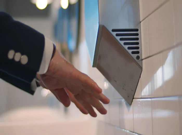 Close up of man in suit drying hands on commercial hand dryer.
