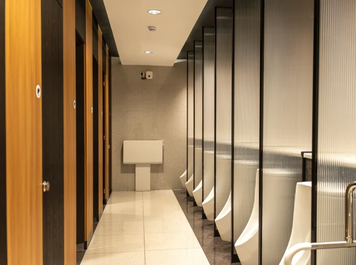 Empty washroom with ambient lighting, wooden doors, and urinals.