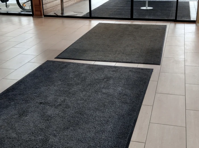 Two black dust control mats in a commercial building entrance.